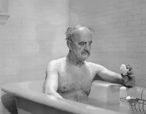 Irritated: Man in bathtub glaring at soap