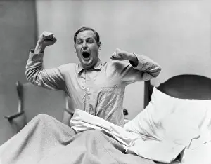 Singular: Man in bed waking up yawning and stretching