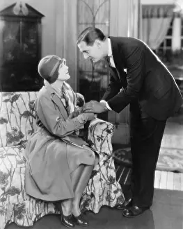 Consoling: Man bending over a woman sitting on a sofa