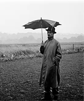 Raincoat: Man with broken umbrella stands in pouring rain