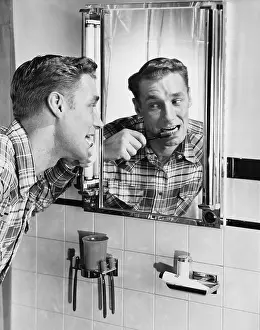 Bathrooms: Man brushing his teeth in bathroom mirror