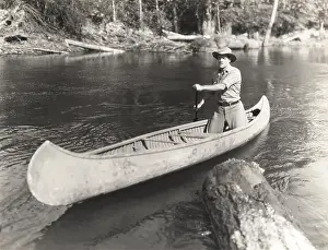 Canoeing: Man canoeing down river