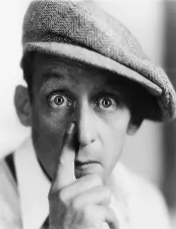 Startling: Man with cap putting his finger to nose