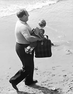 Sleeved: Man carries small girl along the beach