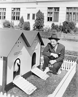 Abode: Man crouching next to duck house