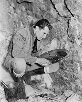 Seriousness: Man crouching and panning for gold