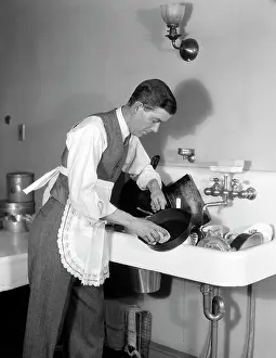Ferrous: Man doing the washing up at a kitchen sink
