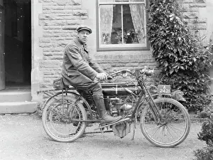Doorstep: Man on an early motorcycle in front of a house