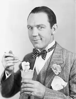 Lapel: Man eating an ice-cream out of a glass with a straw