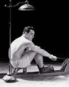Solutions: Man Exercising on Rowing Machine Sitting Under