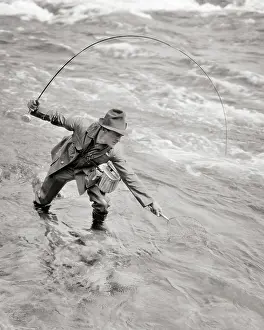 Rewarding: Man Fisherman Standing in Stream Bending Over with Net