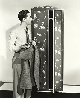 Closet: Man hanging up blazer in armoire