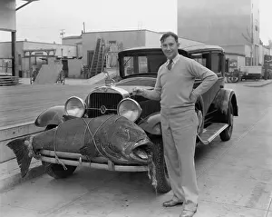 Bumper: Man with large fish tied to the front of his car