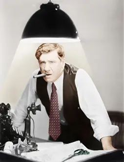Glows: Man leaning over a desk with a ceiling light shining on him