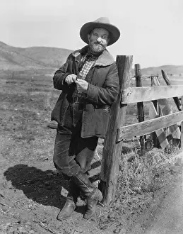 Durable: Man leaning against fence post