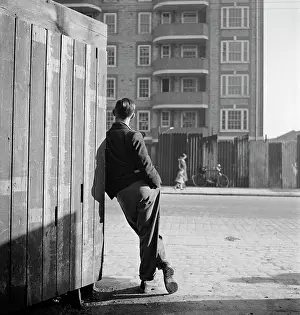 Enclosing: A man leaning on a street corner hoarding