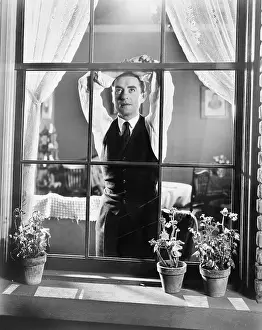 Daydream: Man leaning against a window while day dreaming