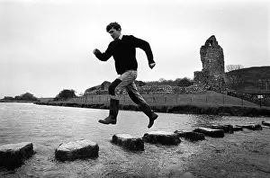 Bounding: A man leaps along the stepping stones at Ogmore Castle