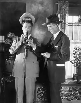 Thirtysomething: Man lighting a long pipe while his hat is lifting