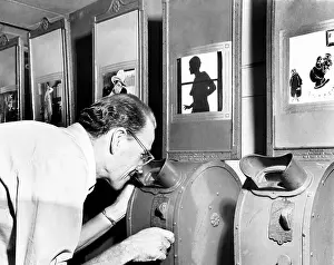Noticing: Man looking into a nickelodeon film machine