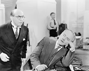 Exhausting: Man looking shocked at a sleeping businessman in the office