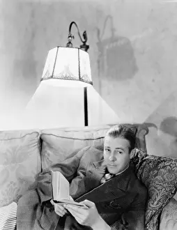 Waist Up: Man lying on a couch and holding a book