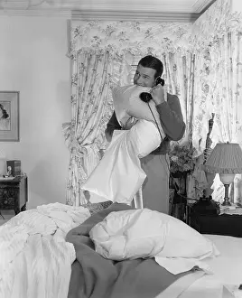 Pillows: Man making bed and talking on phone