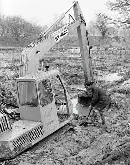 Puddles: Man with mechanical digger in a muddy field