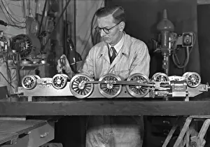 Screwdriver: Man in overalls working on miniature train