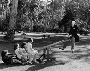 Cooperate: Man playing with children on a seesaw