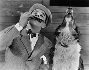 Collaborate: Man playing harmonica with howling dog