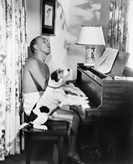 Mockery: Man playing a piano with his dog next to him