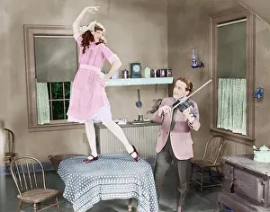 Violinists: Man playing violin for woman dancing on table