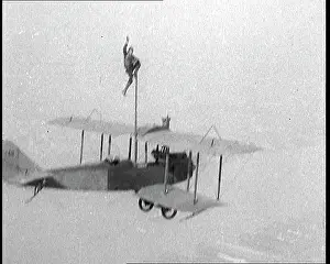Squatting: Man Pole Squatting On Top of a Flying Biplane