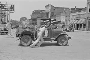 Greensboro: Man pushing broken down car 1930s