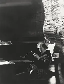 Periodical: Man reading newspaper from large stack