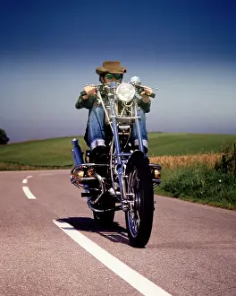 Headlamp: Man Riding Custom Built Chopper Motorcycle on Highway