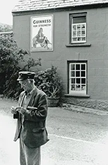 The Japics Historic Image Collection: Man rolling cigarette in the street, Ireland