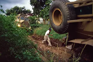 Rutted: A man runs between two armoured military vehicles