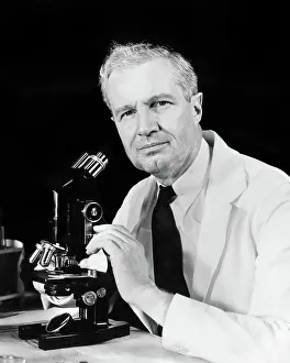 Progressing: Man Scientist Using Microscope Wearing a White Lab Coat a