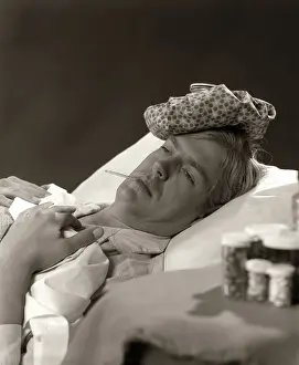 Sufferer: Man in sick in bed with thermometer in mouth