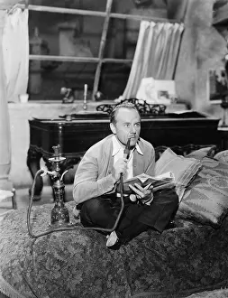 Close Crop: Man sitting on a bed smoking his water pipe