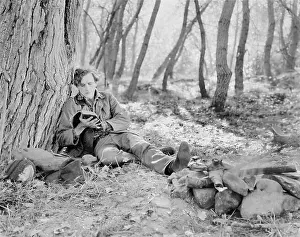 Ablaze: Man sitting next to a fire in the woods and reading a book