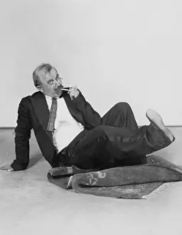 Irritated: Man sitting on floor lighting cigarette