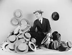 Options: Man sitting on the floor surrounded by hats