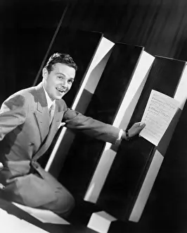 Oversize: Man sitting with oversized books holding sheet music