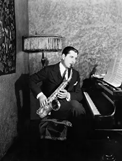 Mustaches: Man sitting at piano playing saxophone