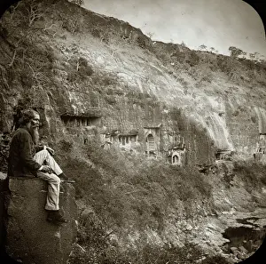 Ajanta: A man sitting on a stone block next to a low cliff face