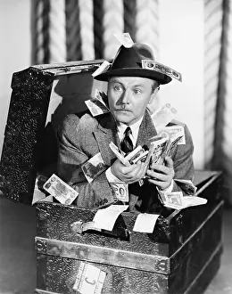 Witty: Man sitting in a trunk with money in his hands