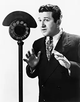 Waist Up: Man speaking into a microphone